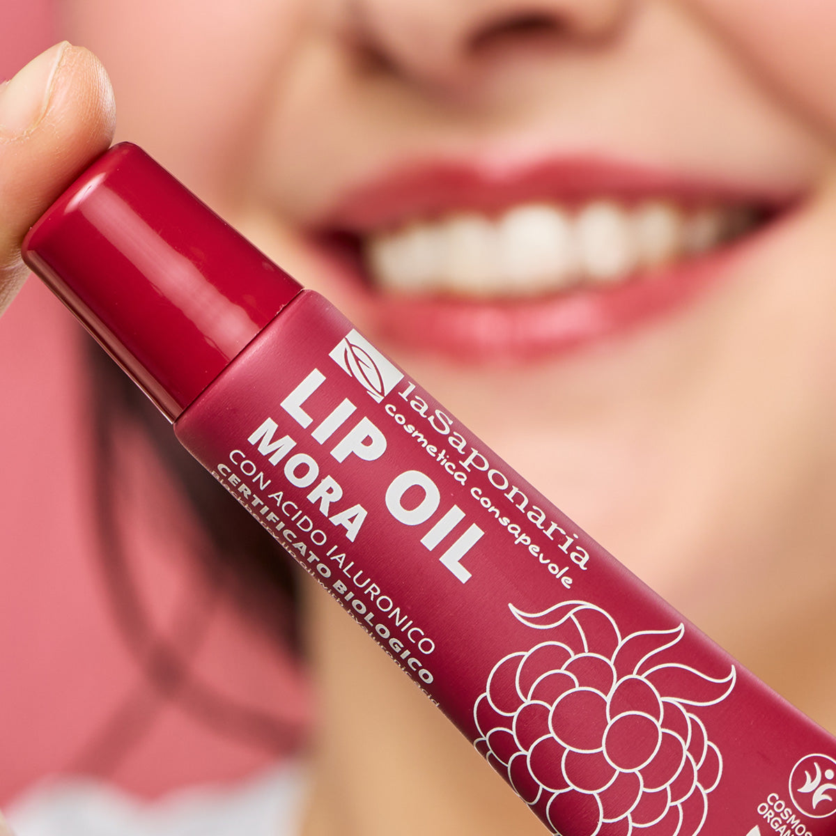 Imagem de lábios com cor vibrante vermelho escuro e embalagem do Óleo Labial biológico Amora — Cor, Volume e Nutrição da La Saponaria