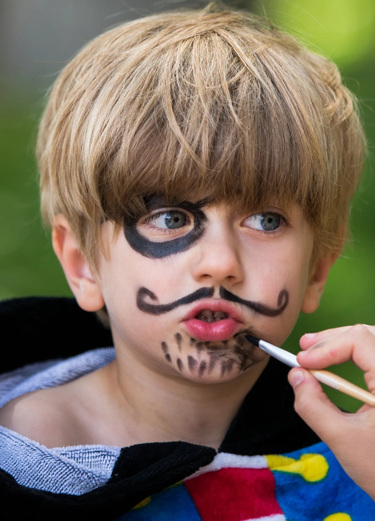 Menino a ser pintado com a Tinta facial biológica à base de água - Preto da Namaki - caixa aberta