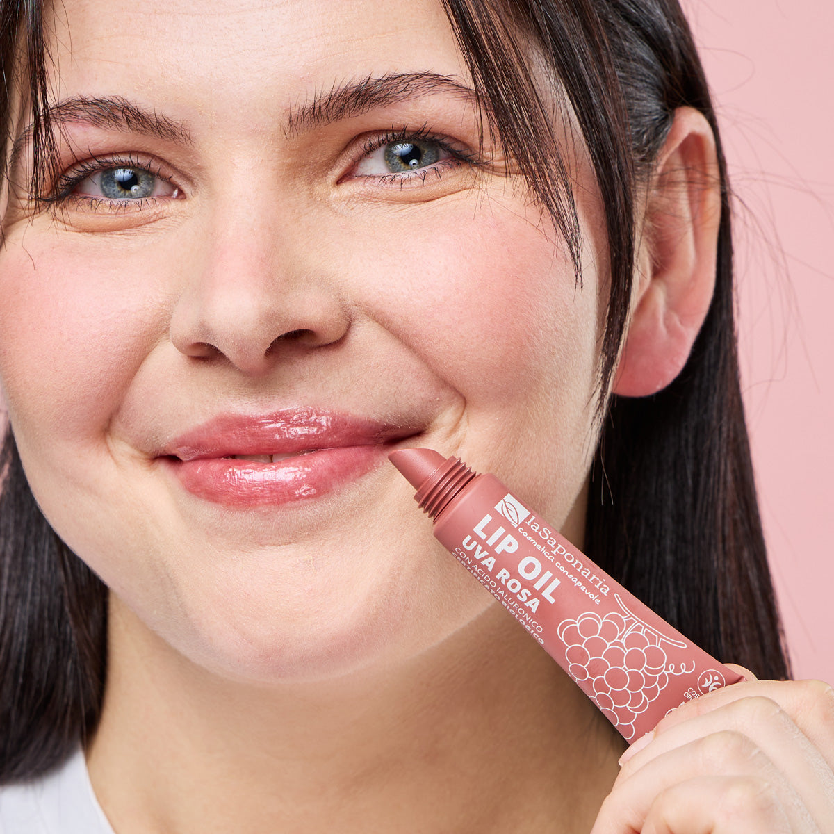 Imagem de lábios brilhantes e rosados e embalagem do Óleo Labial Biológico Uva Rosa — Cor, Volume e Nutrição da La Saponaria