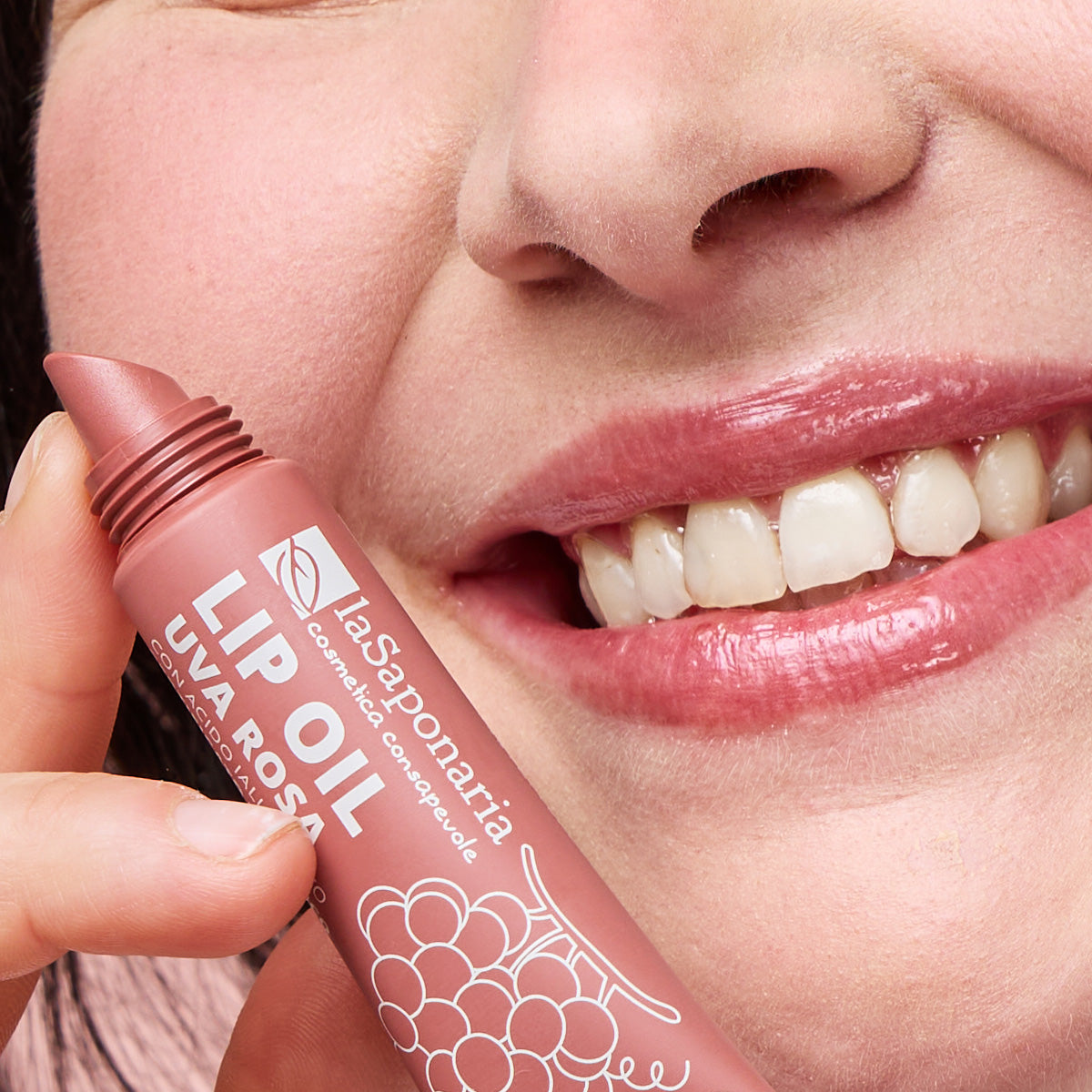 Imagem de lábios brilhantes e rosados e embalagem do Óleo Labial Biológico Uva Rosa — Cor, Volume e Nutrição da La Saponaria