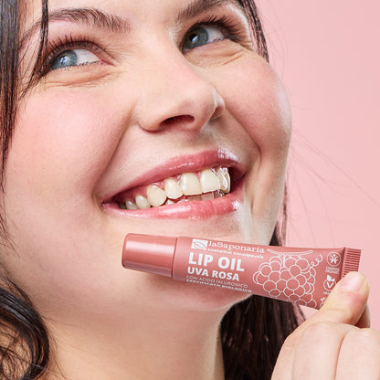 Imagem de lábios brilhantes e rosados e embalagem do Óleo Labial Biológico Uva Rosa — Cor, Volume e Nutrição da La Saponaria